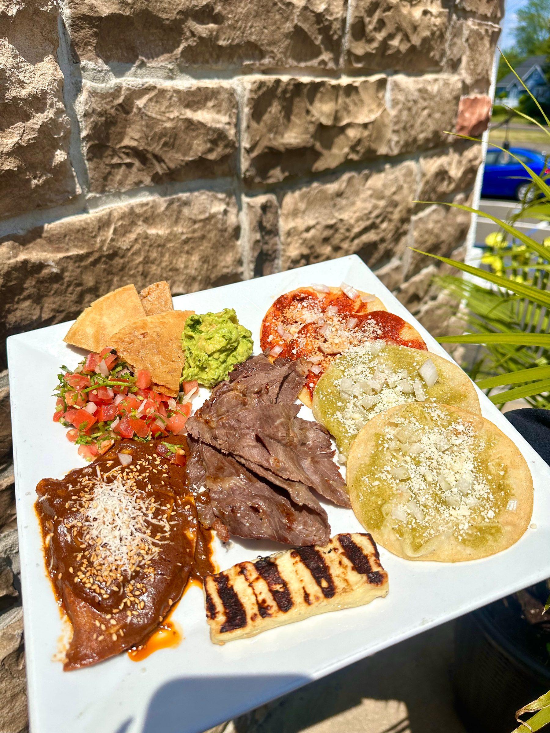 A platter of cesina, an enchilada de mole, red and green chalupas, grilled queso frito, guacamole, pico de gallo and chips
